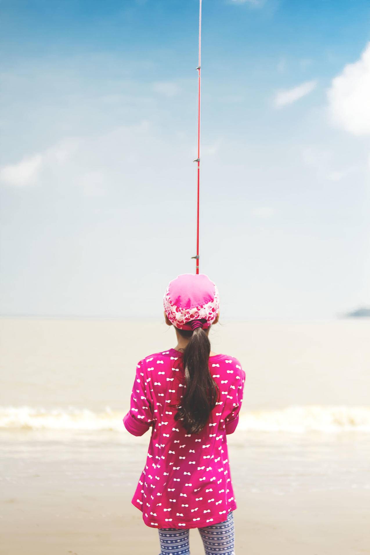 女人穿着粉红色长袖衬衫拿着红色钓竿