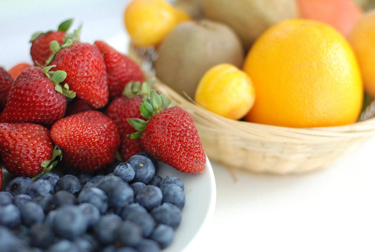 Red,Strawberry,蓝色的浆果在白色盘子附近棕色编织篮子