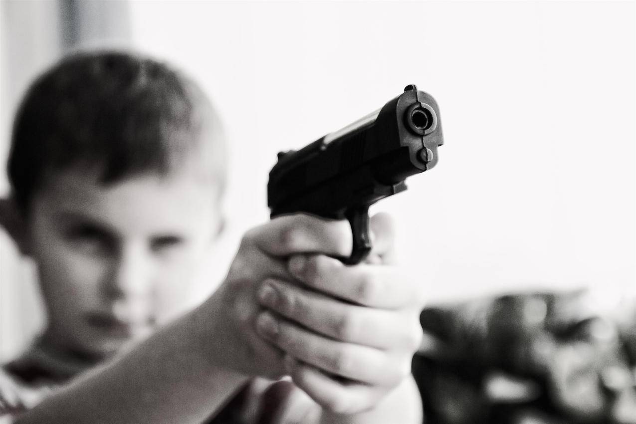 瞄准玩具枪的男孩的灰度照片