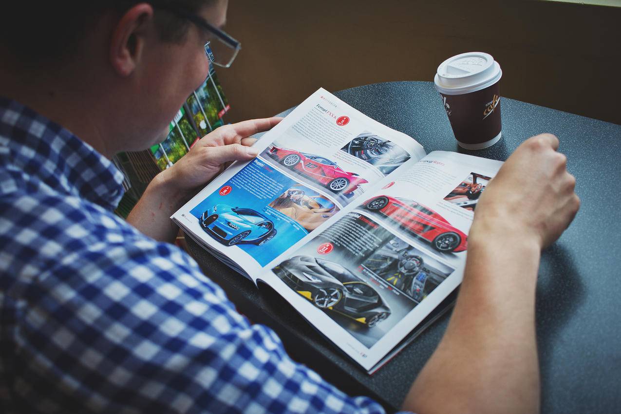 穿蓝白相间衬衫的男士阅读汽车杂志