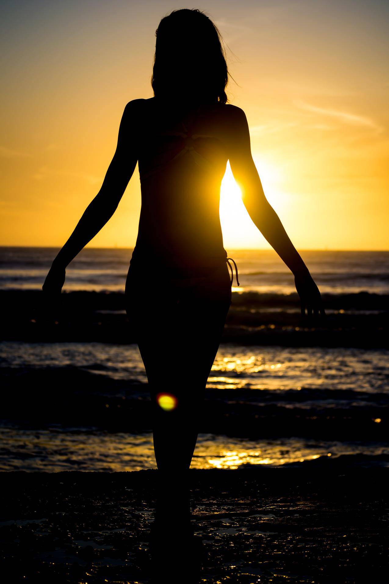 日落时沙滩上散步的女人