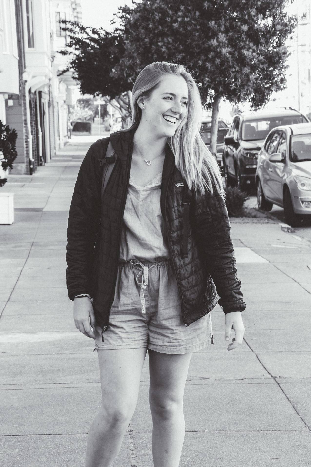 微笑的女人穿着夹克站在路上的灰色照片
