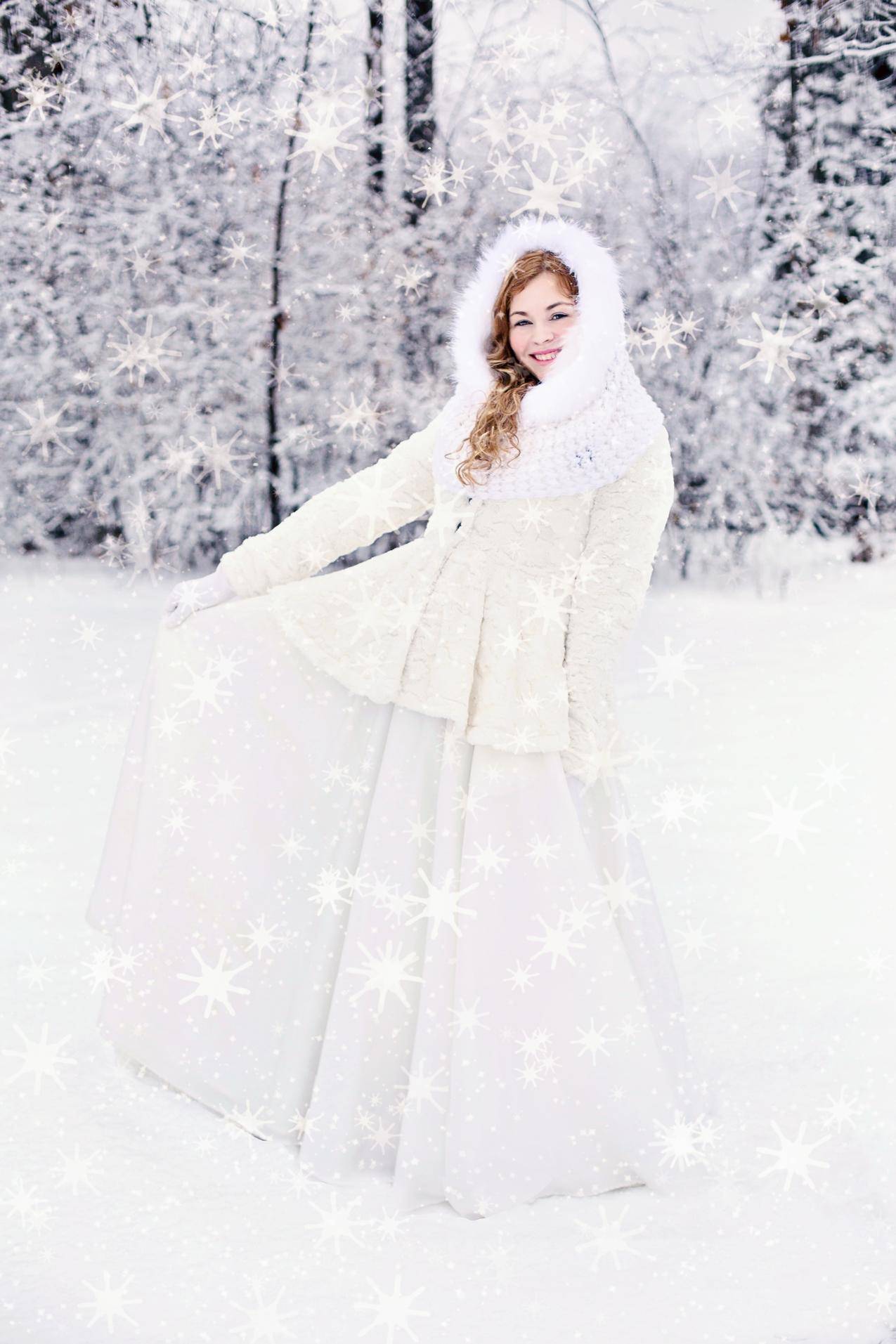 穿着雪白衣服的女人站在积雪覆盖的树后面的雪地上