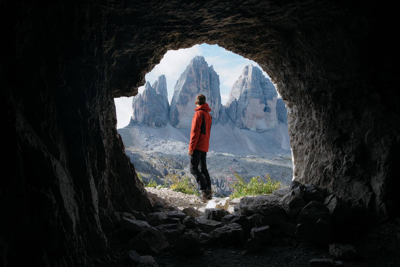 身穿红色夹克的男子站在Cave的三座山前