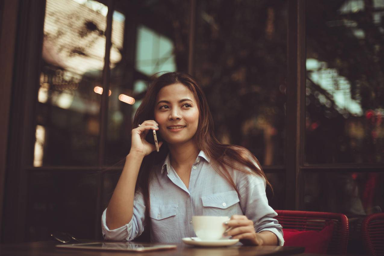 在咖啡馆里使用手机的年轻女性肖像