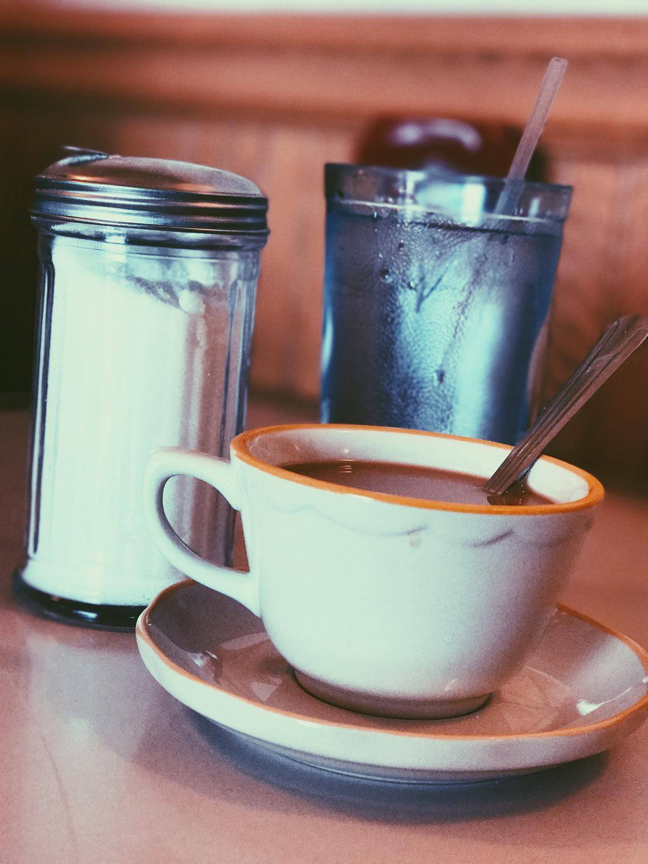 白陶瓷杯在调味品搅拌器旁加满咖啡