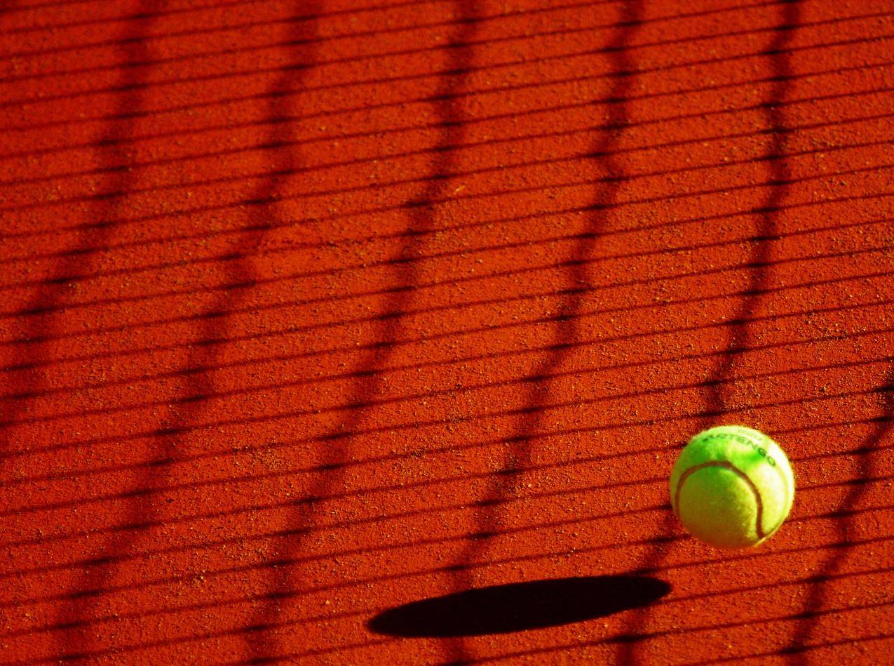 阳光灿烂的红色地板上的绿色网球