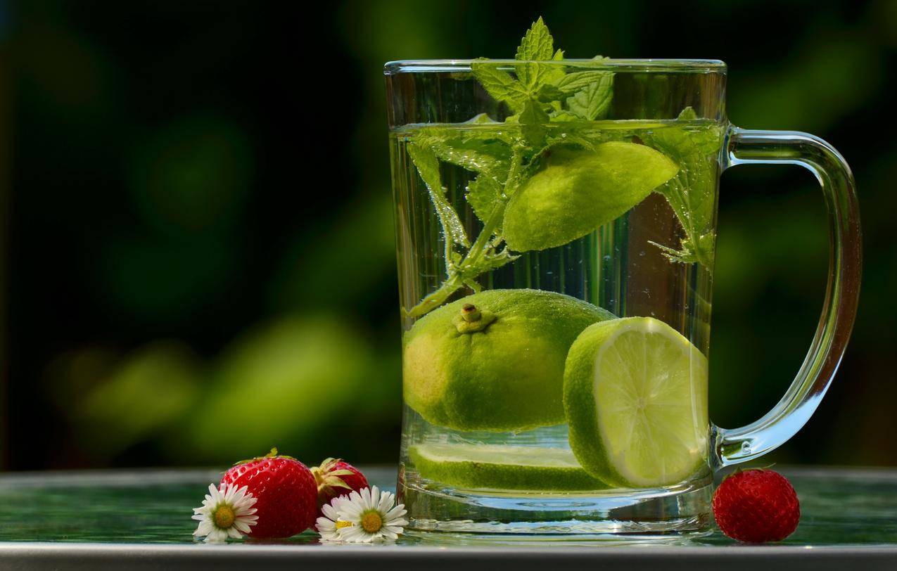 绿色圆形水果在透明玻璃杯上加水