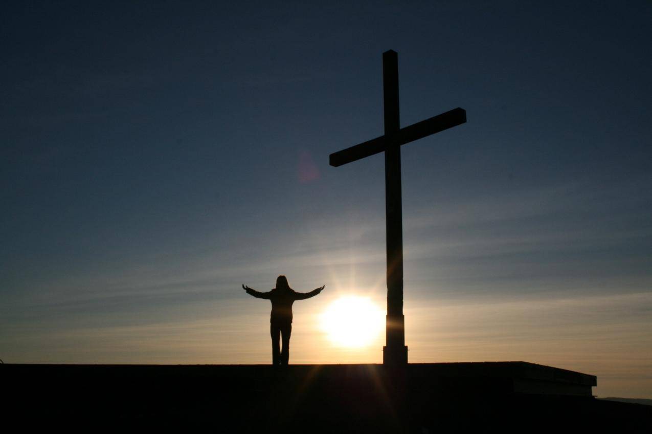 日落时站在十字架旁的人影