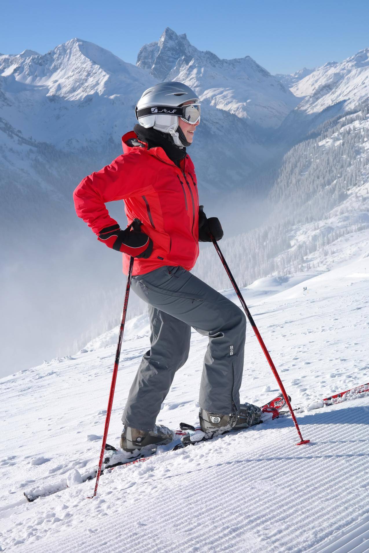 穿红色夹克的妇女戴头盔和滑雪板
