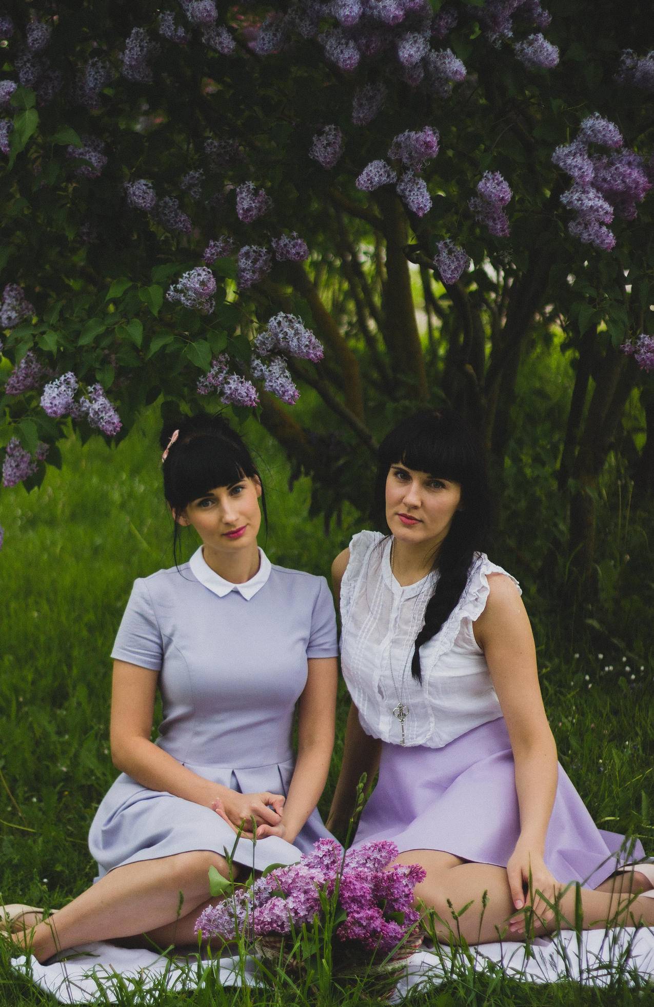 两个女人穿着紫色衣服并肩坐在草地上