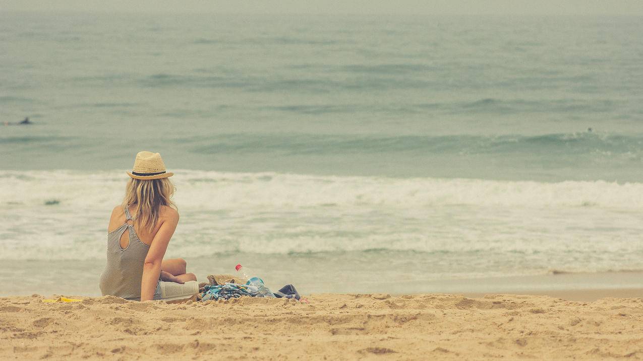 坐在海滩上的女生背影图片