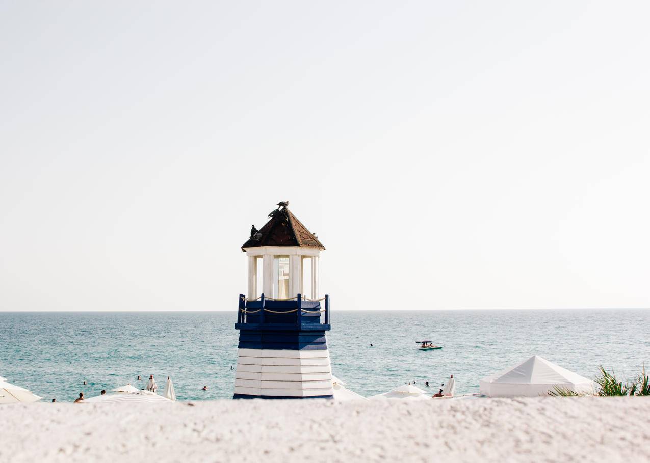 海滩附近蓝色和白色画灯塔的图片