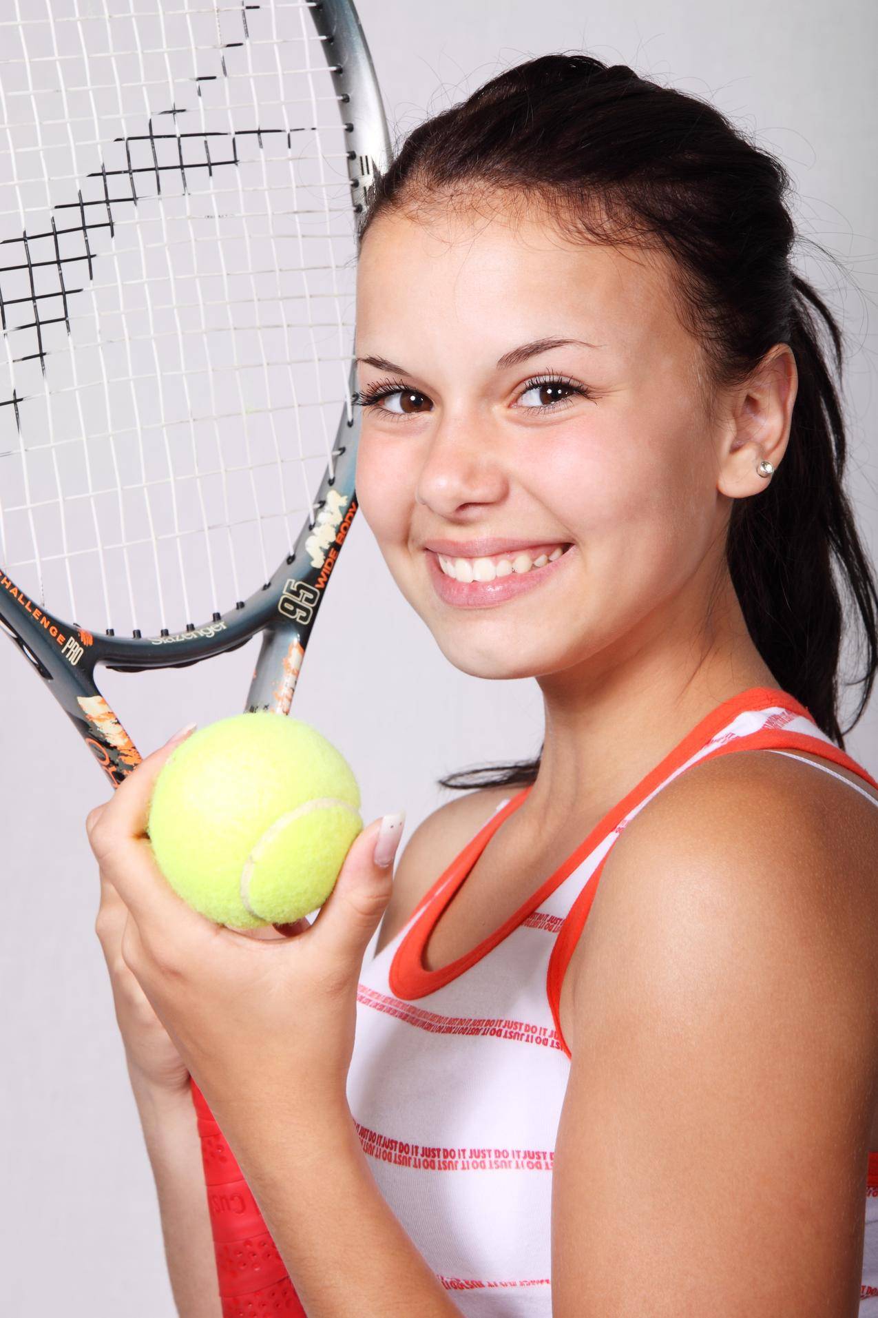 白色和橙色条纹的女孩顶着黑色的网球拍