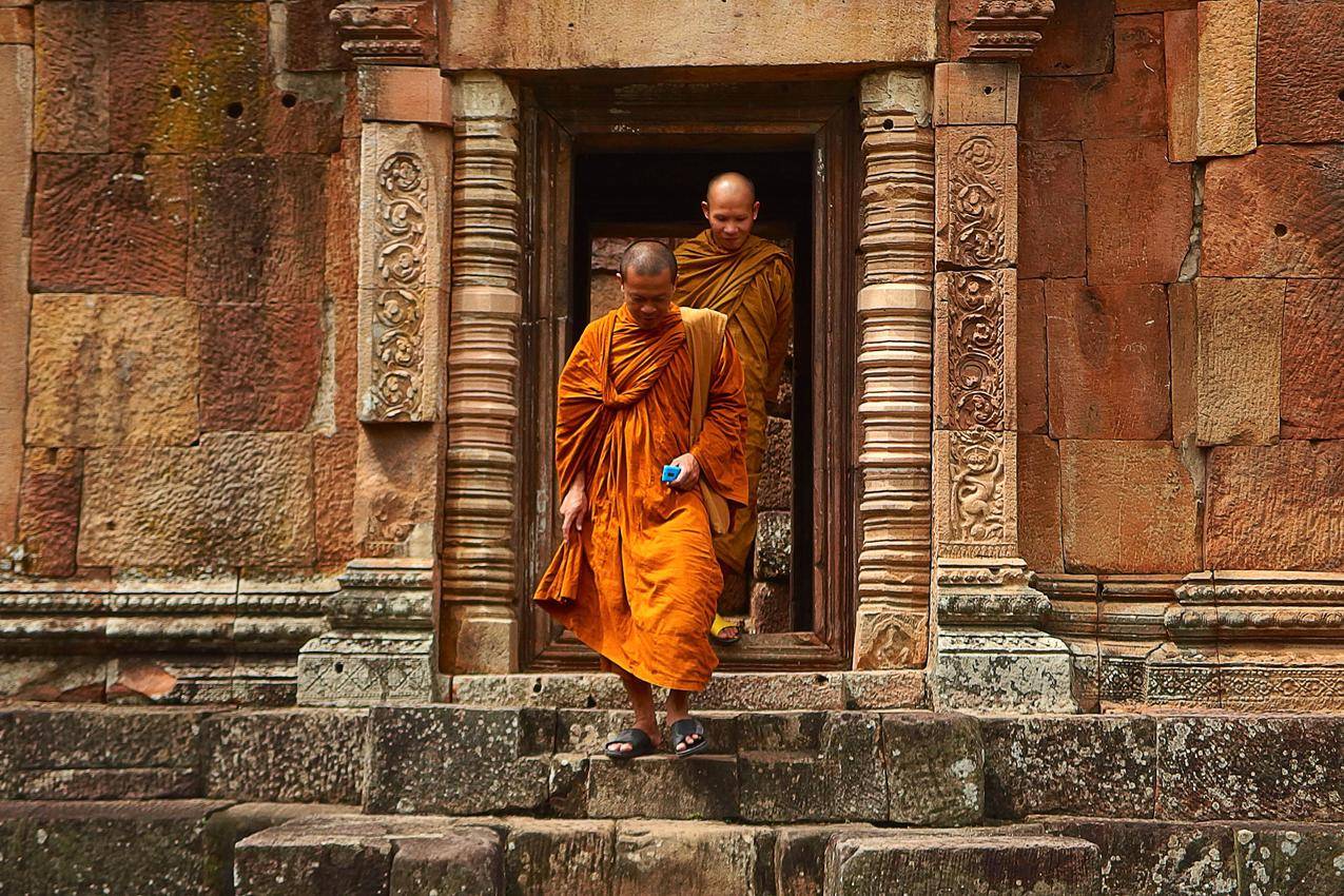 两个穿着橙色长袍的僧侣走下混凝土楼梯